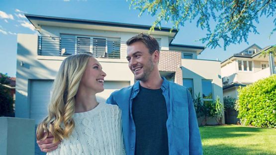 Couple smiling in front of their first home.