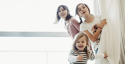 Three young girls playing behind a curtain
