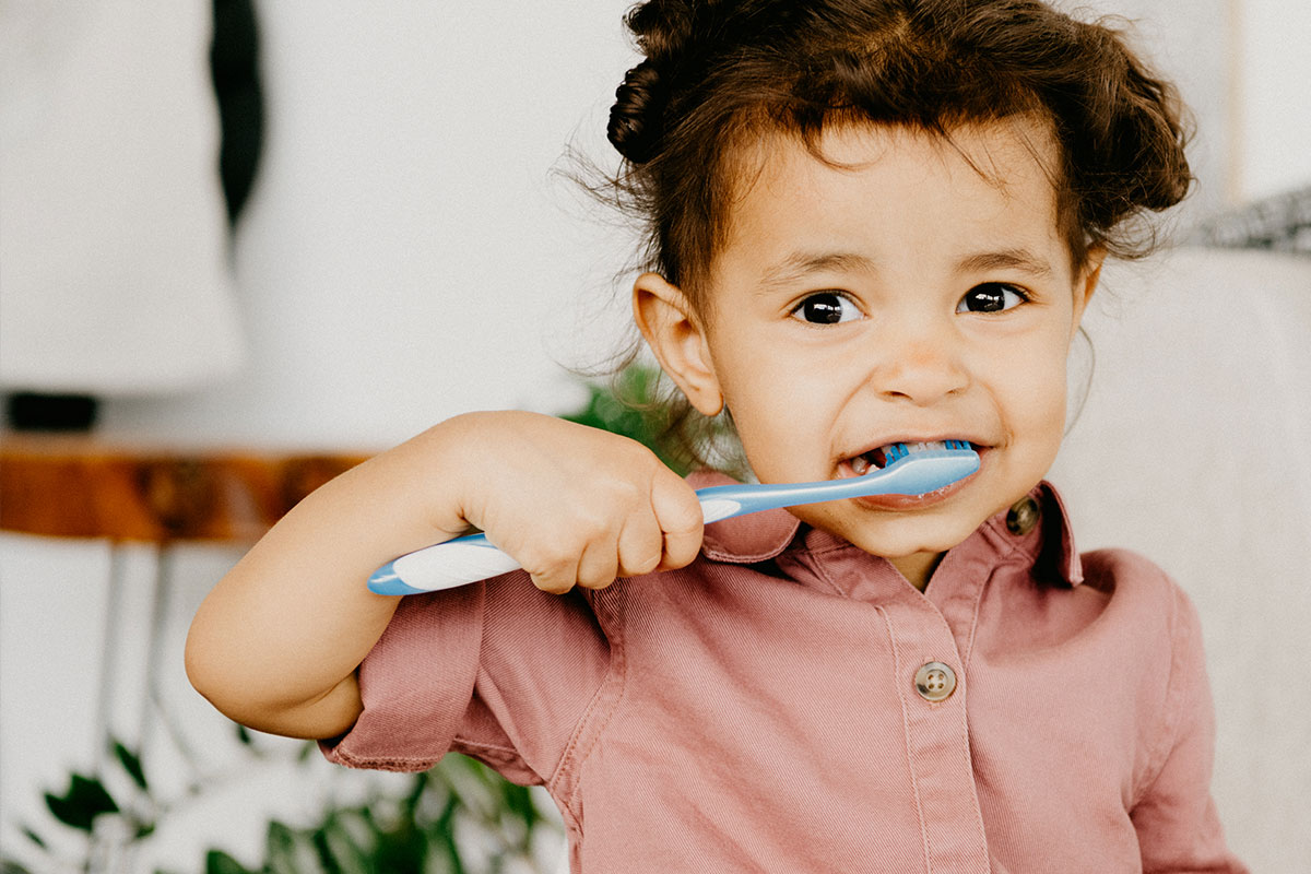 Girl in pink brushing teeth