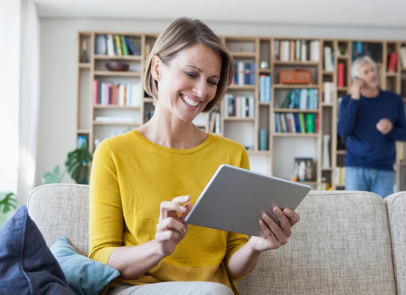 A Woman searching through GreenShield insurance options on her tablet while sitting on her couch